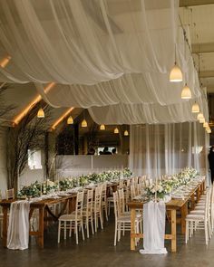 the tables are set up with white linens and greenery for an elegant wedding reception