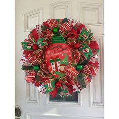 a red and green christmas wreath hanging on the front door