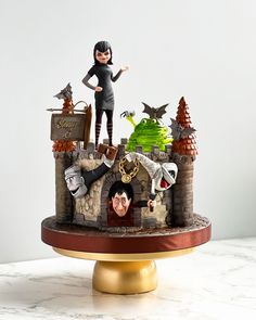 a cake decorated with an image of a woman and two witches on top of a castle