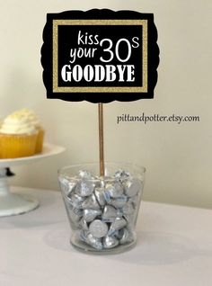 a cupcake and some candy on a table with a sign that says kiss your 30's goodbye