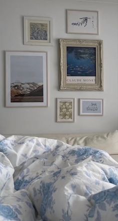 a bed with blue and white comforter next to pictures on the wall