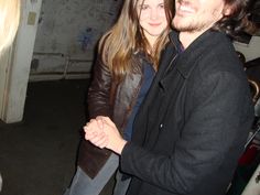 a man and woman standing next to each other in a room with graffiti on the walls