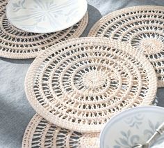 some plates and bowls on a table with doily around the placemats that have been cut into circles