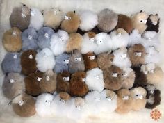 a bunch of stuffed animals that are on a white fur covered surface, with one bear in the middle