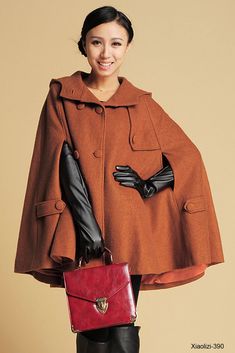 a woman in a brown coat and black gloves holding a red purse