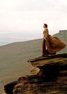 a woman standing on top of a rock formation