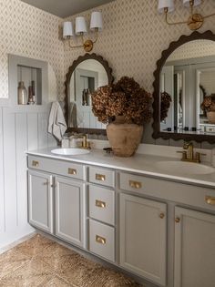 a bathroom with two sinks and mirrors on the wall next to it is decorated in gold