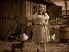 an old photo of a woman standing in front of a barn with chickens and pigs