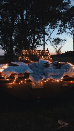 a truck is covered with blankets and lights in the back yard at night or dawn