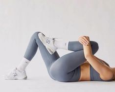 a woman is laying on the floor with her legs crossed and wearing grey sportswear