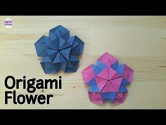 two origami flowers sitting on top of a wooden table next to each other