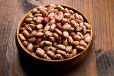 a wooden bowl filled with peanuts on top of a table