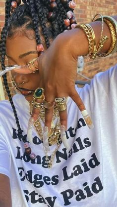 a woman with dreadlocks pointing to the side while wearing a white t - shirt