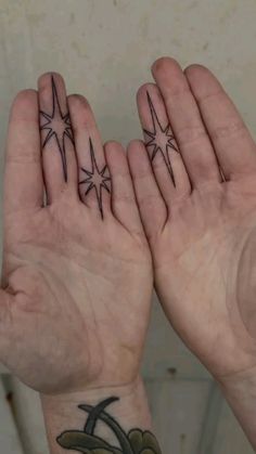 two hands with star tattoos on their palms