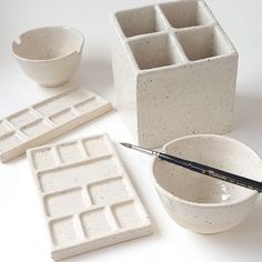 a white table topped with cups and bowls filled with ice cubes next to a pen