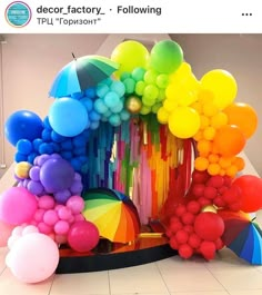 there are many balloons and umbrellas on the floor in front of this colorful display