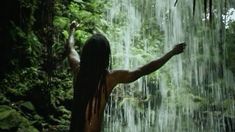 a woman standing in the rain with her arms outstretched