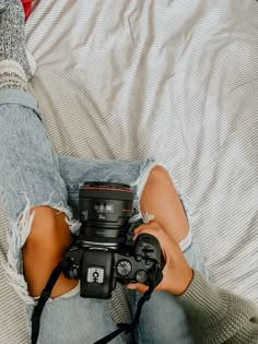 a woman laying on top of a bed holding a camera