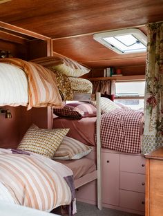 bunk beds in a small room with pillows and blankets on the bottom bunk, next to a window