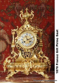 a gold clock sitting on top of a table in front of a red and white wall