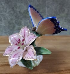 two butterflies sitting on top of a pink and white flower vase with water droplets in it