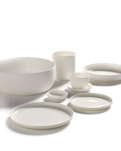 white dishes and cups are arranged on the table top, with one empty bowl in the middle