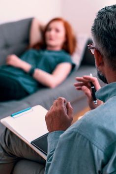 a man sitting on a couch with a laptop computer in his lap and a woman laying down behind him