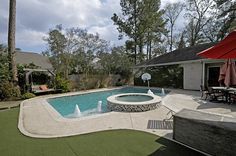 a backyard with a swimming pool, patio furniture and an umbrella over the pool area