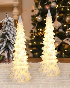 two small white christmas trees sitting on top of a table