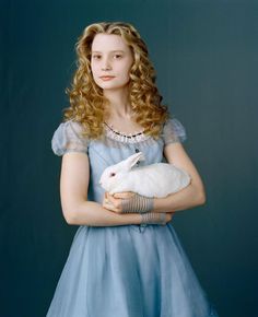 a woman in a blue dress holding a white rabbit