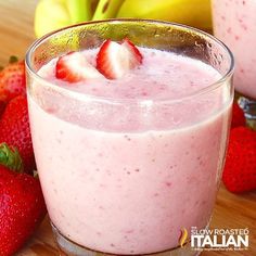 two glasses filled with fruit sitting on top of a wooden table next to bananas and strawberries