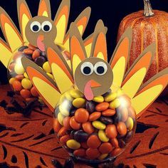 two turkeys made out of candy sitting next to pumpkins