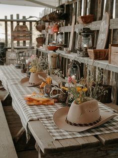 several hats are lined up on a table with flowers and other items in the background