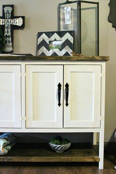 a white cabinet sitting on top of a hard wood floor next to a cross and other items