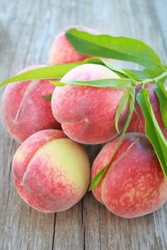 four peaches with green leaves on top of them