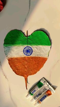 a heart shaped piece of paper with the flag of india on it next to batteries