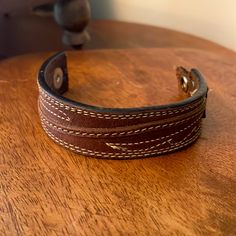 a close up of a leather bracelet on a wooden table