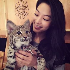 a woman holding a cat in her arms and looking at it's face while smiling