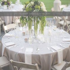 the table is set with white linens, silverware and green floral centerpieces