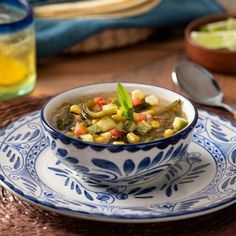 a blue and white bowl filled with soup on top of a wooden table next to other dishes