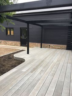 a large wooden deck in front of a black building with an awning over it