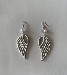 two pairs of earrings with white wings on them