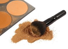 a makeup brush and powder on a white background