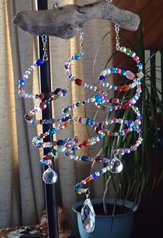 an image of a wind chime hanging from a tree branch with beads and crystals on it