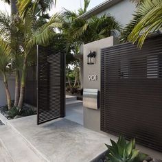 an entrance to a modern home with palm trees in the foreground and a toilet on the other side