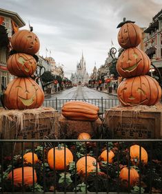 several pumpkins stacked on top of each other in front of a gated street