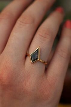 a woman's hand wearing a gold ring with a black stone in the middle