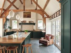 a kitchen with an island and chairs in the center, surrounded by wood framed windows