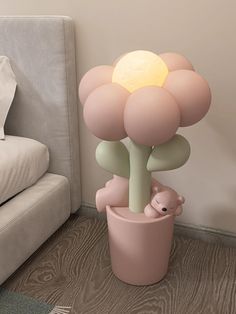 a pink flower pot sitting on the floor next to a stuffed animal and a lamp