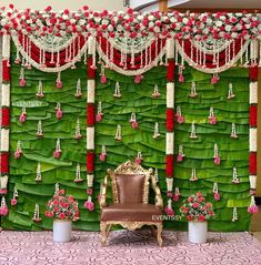 a chair sitting in front of a green backdrop with red and white flowers on it